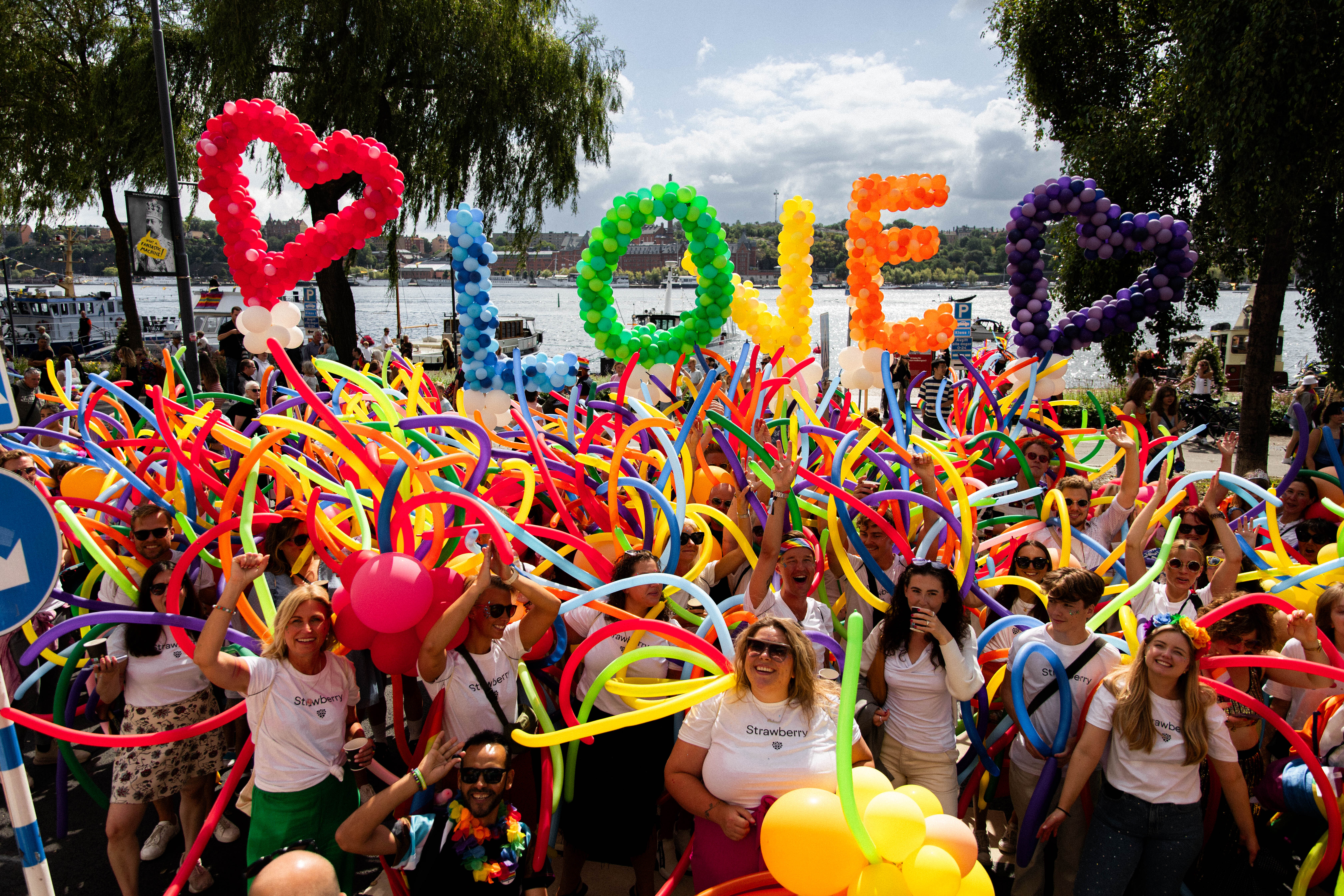 Pride celebration with lots of colourful balloons, people and balloons spelling LOVE