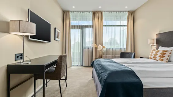 Ett modernt hotellrum på Quality Hotel Ulstein med en bekväm säng, ett skrivbord och stora fönster som släpper in naturligt ljus.