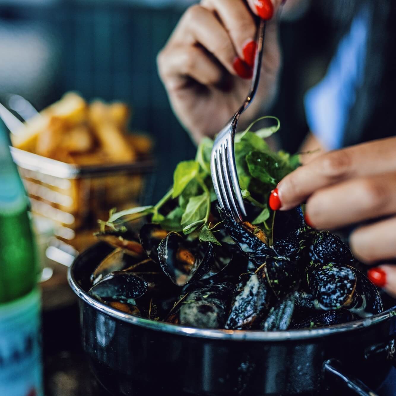 Woman eating mussles and fries at restaurant The Social Bistro & Bar.