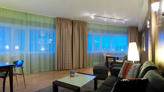 A well-lit, modern living room with furniture and large windows, suggesting a comfortable, stylish interior space.