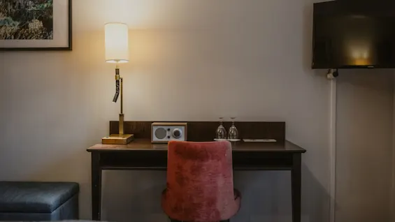 A comfortable desk area in a hotel room, featuring a lamp, radio, and TV, ideal for guests at Home Hotel Kung Oscar.