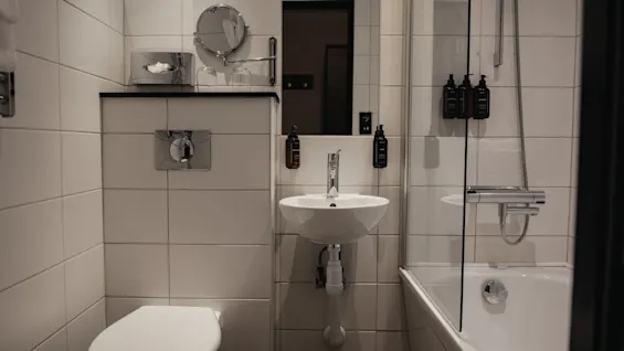Hyvin varusteltu kylpyhuone, jossa on wc, pesuallas peilillä ja yhdistetty suihku ja kylpyamme. Valmis käyttöön.