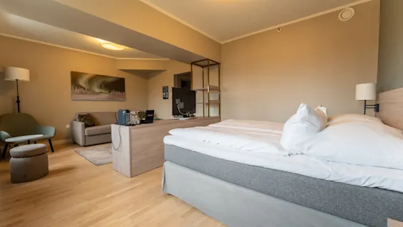 Et koselig hotellrom på Quality Hotel Saga, med en komfortabel seng og et separat oppholdsrom med sofa og TV.