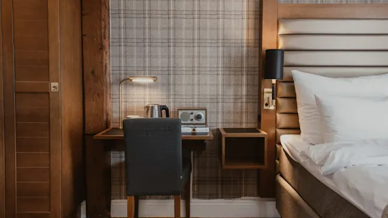 A warm and inviting hotel room with a functional desk setup and a plush bed, perfect for relaxation or work.