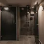 Et moderne og elegant dusjområde med mørke flislagte vegger og gulv, med en glassvegg og en mørk personverndør.