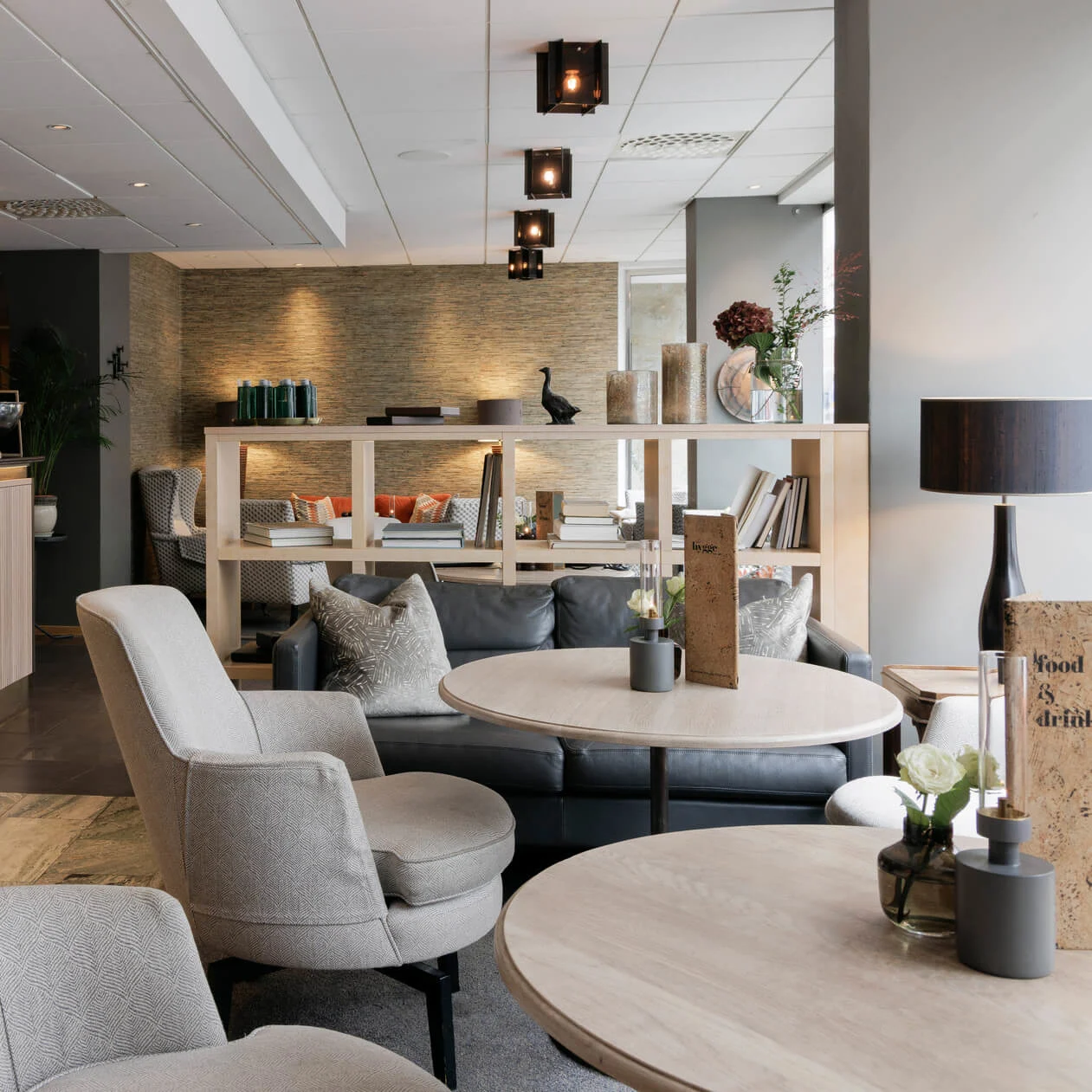 Modern loungeområde med bekväma sittplatser och en bardisk, inrett i en neutral färgskala med elegant belysning.