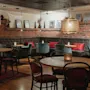 En varm och inbjudande restaurang- eller barinteriör med tegelväggar, plyschmöbler, träbord och stämningsfull belysning.