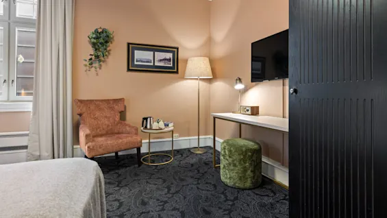 Et varmt og innbydende hotellrom på Home Hotel Gabelshus med en seng, et sitteområde og en funksjonell arbeidsplass.