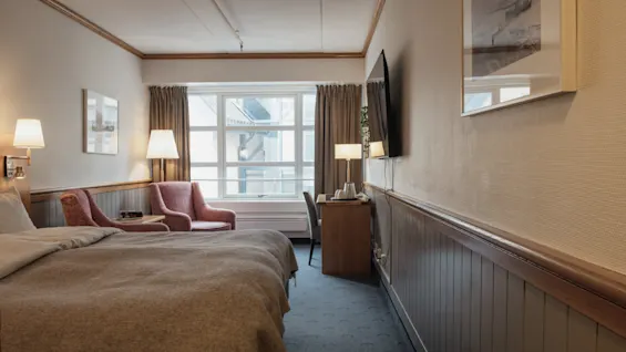 A cozy hotel room with a comfortable bed, seating area, and a desk, perfect for relaxation or work.