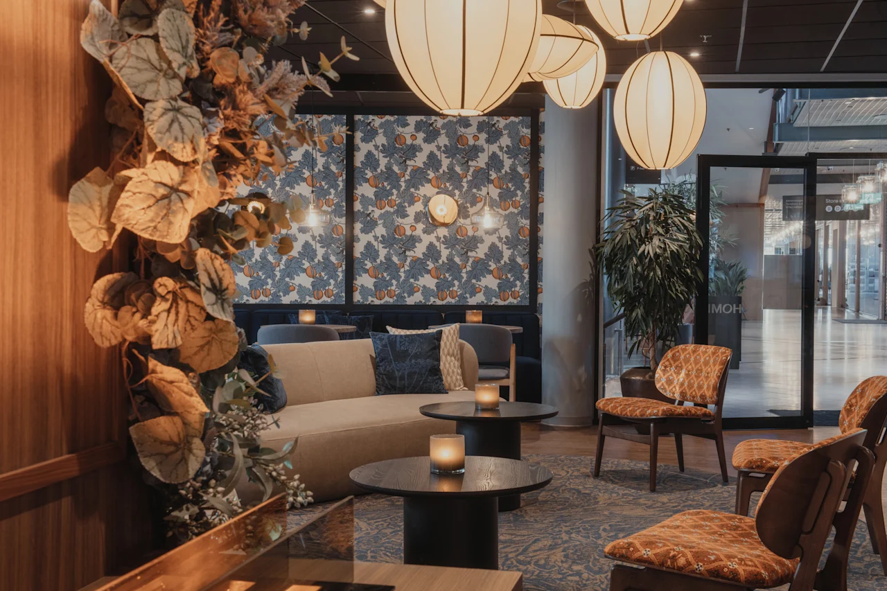 Et stilfullt og innbydende hotelloungeområde med komfortable sitteplasser, varm belysning og dekorative planter, som skaper en koselig atmosfære.