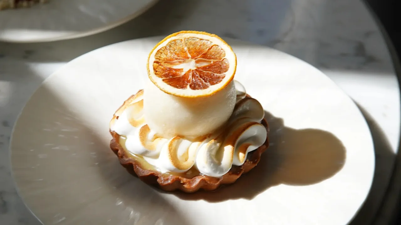 En deilig dessert med marengs og en tørket appelsinskive på en hvit tallerken på Jørgensens Hotel – Restaurant Eydes.