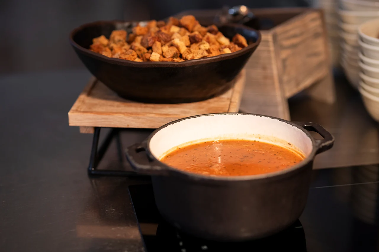 Lämmin keittokattila ja kulho rapeita krutonkeja noutopöydällä, valmiina tarjoiltavaksi.