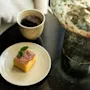 Et lækkert stykke kage med myntepynt og en kop kaffe på et mørkt bord, der antyder en behagelig pause.