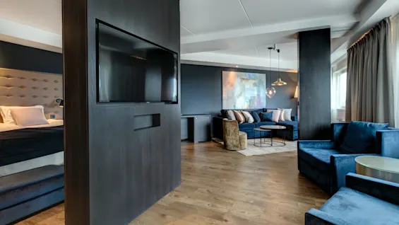 Moderni ja tilava hotellihuone, jossa on tyylikäs oleskelualue, mukavat sohvat ja erillinen makuutila.