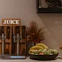 A self-serve juice station with options for orange, apple, pink grape, and water, alongside fresh fruit and croissants.
