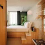 Hobo Oslo hotel room, featuring a minimalist design with a raised bed, wooden storage, and a bright window.
