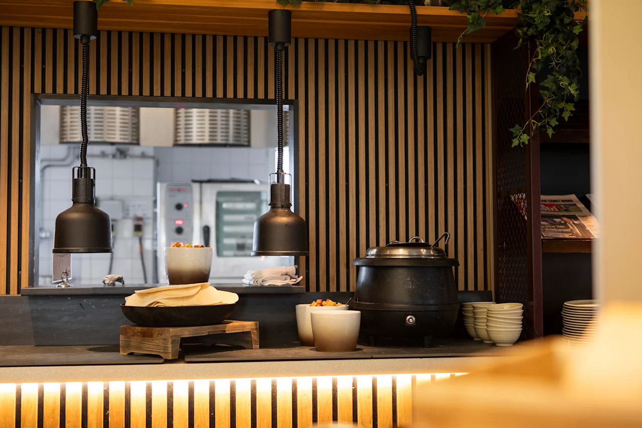 En varm och inbjudande självserveringsstation med varma rätter och färskt tunnbröd, med en glimt av köket.