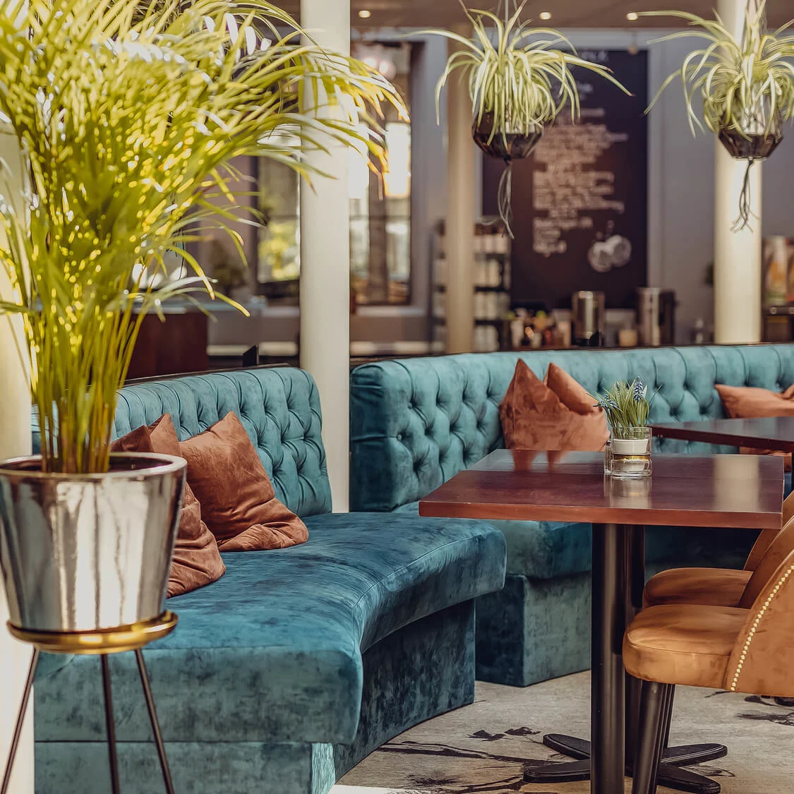 Teal tufted booths and wooden tables in an elegant restaurant setting.