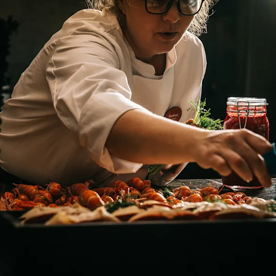 A chef carefully arranging fresh seafood and garnishes on a buffet table.