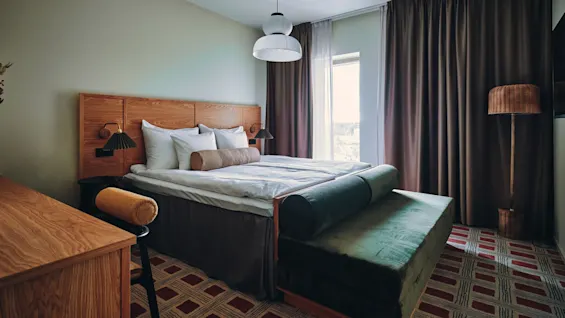 Et koselig hotellrom med en stor seng, en komfortabel benk og et skrivebord, klart for avslapning eller arbeid.