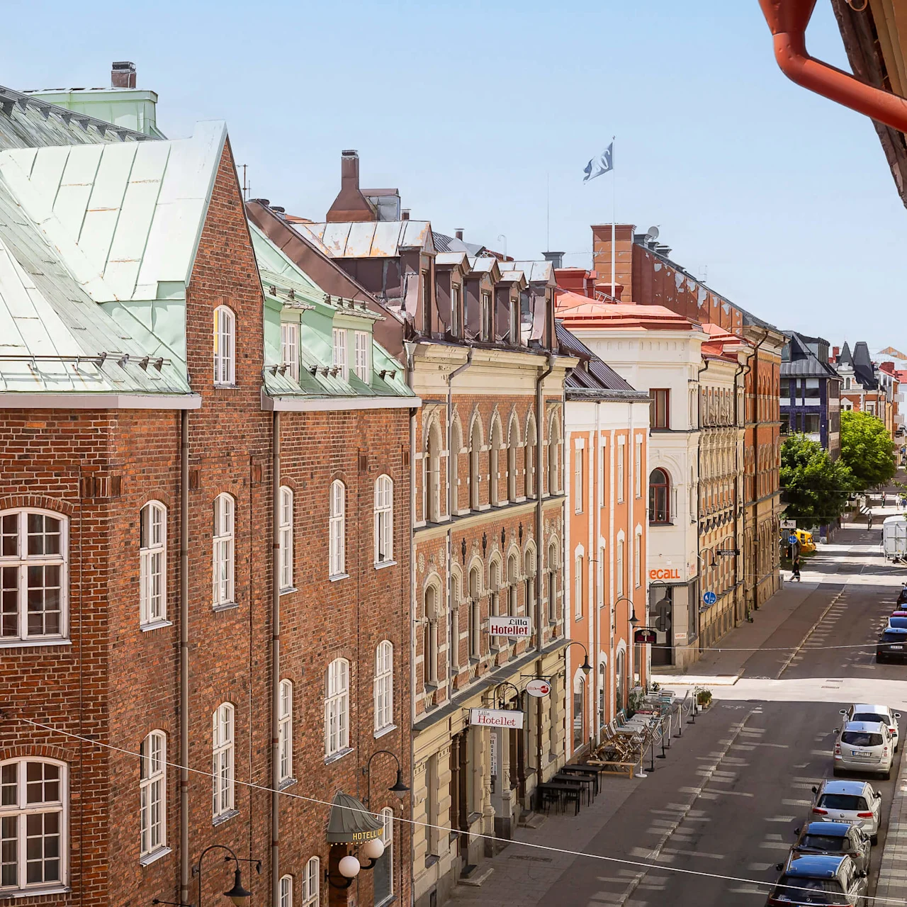 En vy uppifrån av en europeisk gata kantad med flervånings traditionella byggnader på en solig dag.