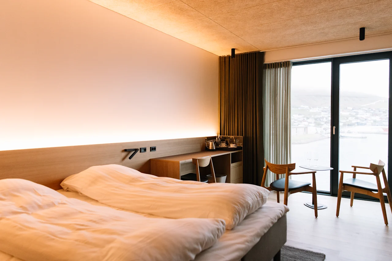 Moderni hotellihuone KG Hotel på Färöarna -hotellissa, jossa on parivuode, puukalusteet ja suuret maisemaikkunat.