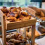 A wooden display stand filled with delicious pastries and bread, including jam-filled danishes and flaky croissants.