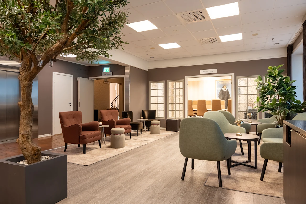 Quality Hotel Saga aula, jossa on viihtyisiä nojatuoleja, suuri puu ja kyltit The Room ja The Board.