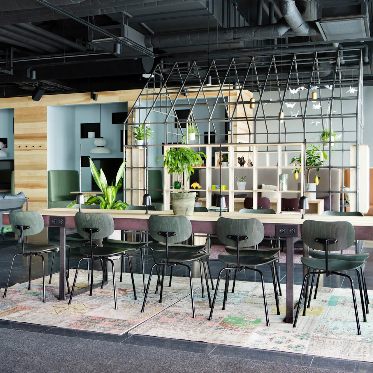 Ett modernt kontorslounge med varierade sittgrupper och dekorativa växter; en stilig, social arbetsplats.