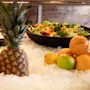 En forfriskende madudstilling med en farverig salat, tropiske frugter og citrus på is, klar til servering.