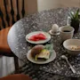 Herkullinen aamiaistarjoilu pilkullisella pöydällä, sisältäen voileivän, hedelmiä, kahvia ja muroja, valmiina nautittavaksi.