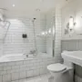 A bright and clean bathroom featuring a bathtub with a shower, a toilet, and a sink, all in a modern design.