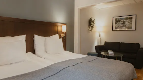 A cozy hotel room at Home Hotel Kung Oscar with a comfortable bed and a separate sitting area for relaxation.