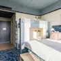 Et lyst og moderne hotelværelse på Hernö Gin Hotel med en stor seng og en køjeseng, perfekt til et familieophold.