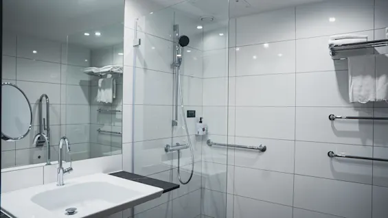 Valoisa ja moderni kylpyhuone Quality Hotel View -hotellissa, jossa on tilava lasisuihku, puhdas pesuallas ja raikkaita valkoisia pyyhkeitä.