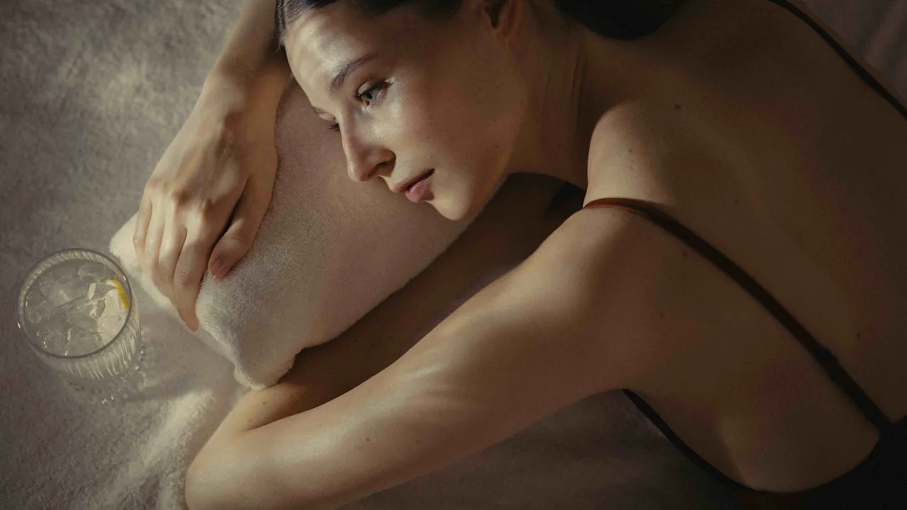 A person relaxing on a soft surface, possibly after a spa treatment, with a refreshing drink nearby.