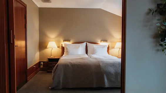 Ett varmt och inbjudande sovrum med en bekväm dubbelsäng, sänglampor och mjuk belysning, vilket skapar en avkopplande atmosfär.