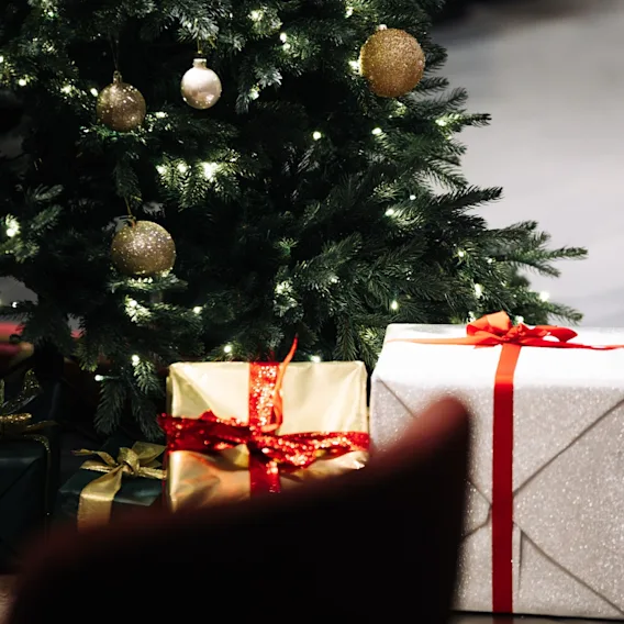 Et festlig juletre med glitrende lys og pynt, omgitt av vakkert innpakkede gaver, klart for høytiden.