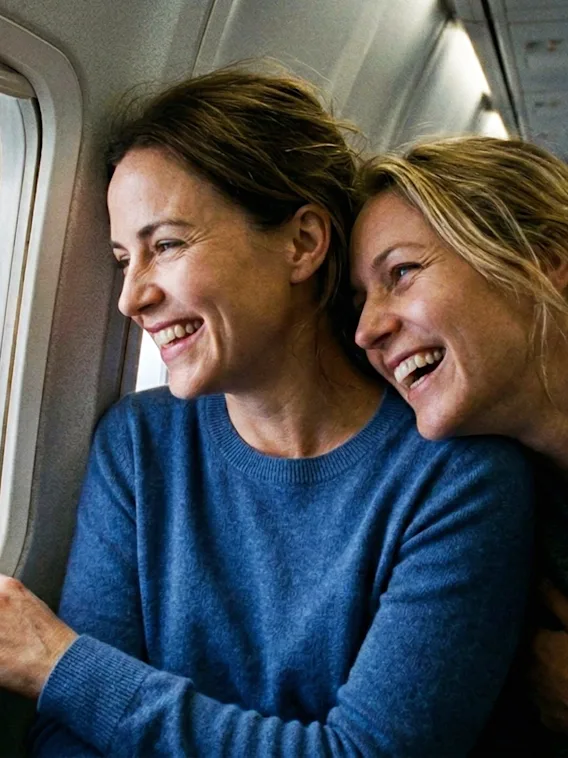 Två glada personer tittar ut genom ett flygplansfönster och njuter av utsikten och varandras sällskap.