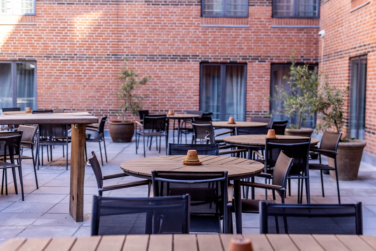 Outdoor patio at Comfort Hotel Vesterbro with wooden tables and chairs, ready for guests to relax or dine.