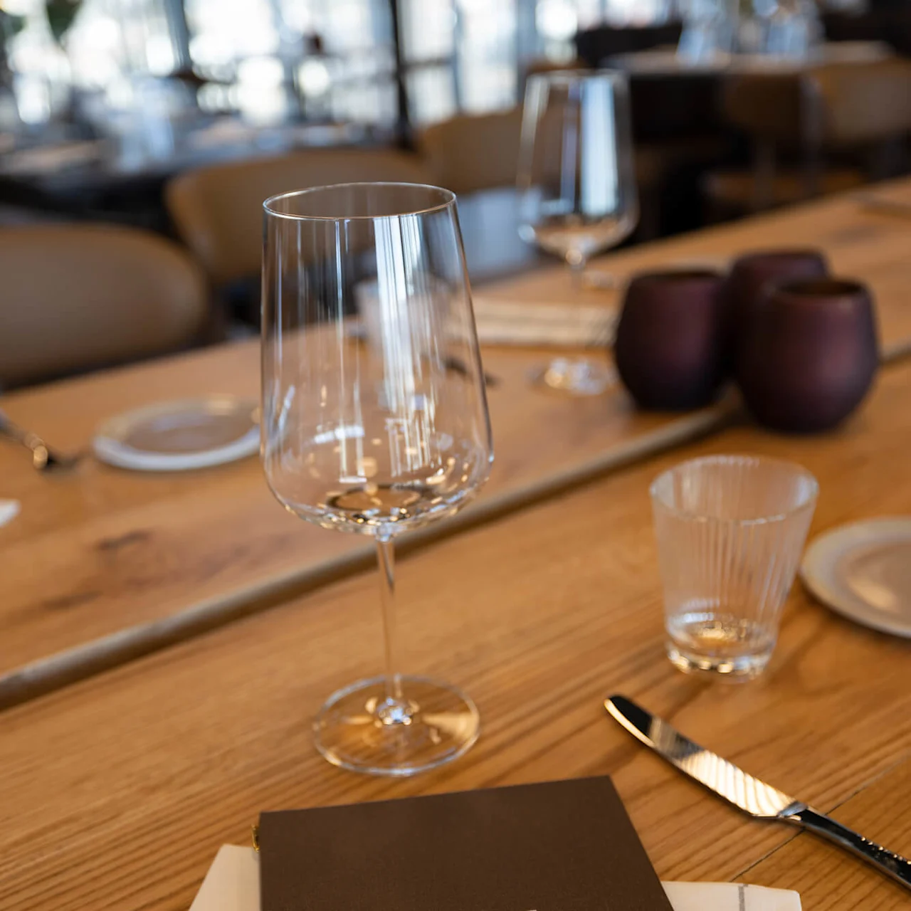 A menu on a restaurant table, titled "1624 RESTAURANT BAR MENY" with glassware and utensils around it.