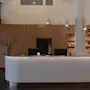 En modern receptionsdisk med rundad design står i en varmt belyst lobby. Bakom den, trähyllor visar flaskor, och en elegant belysning hänger ovanför.