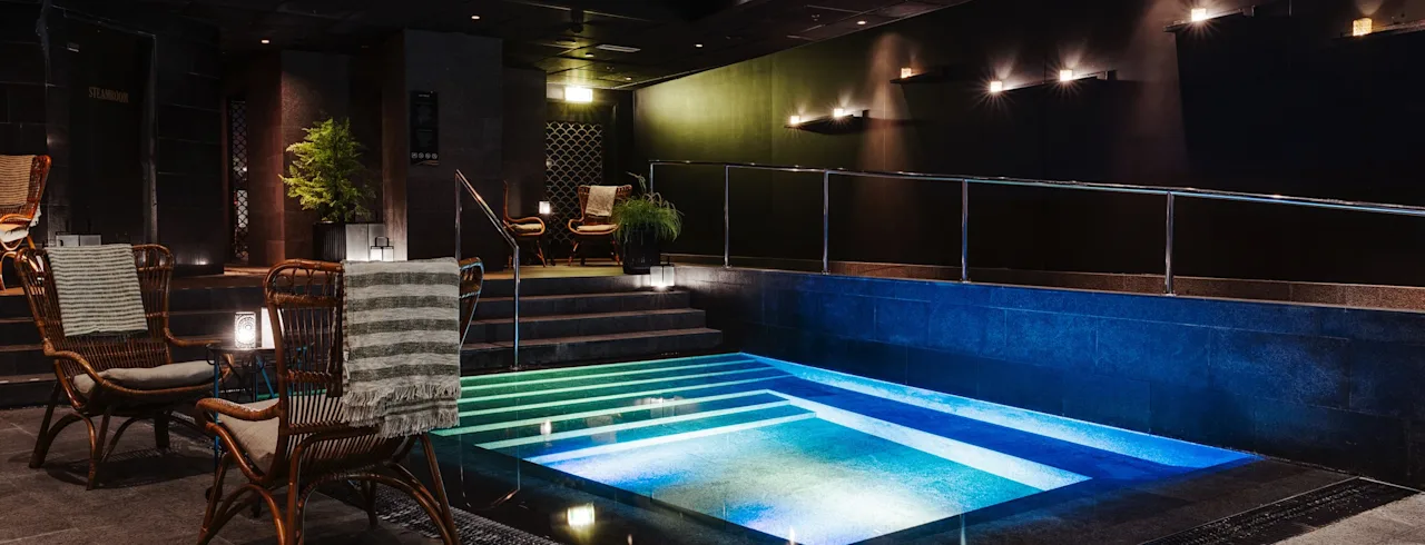 Ett inbjudande inomhuspoolområde på Clarion Hotel Post med mjuk belysning, bekväma sittplatser och en vackert upplyst pool.