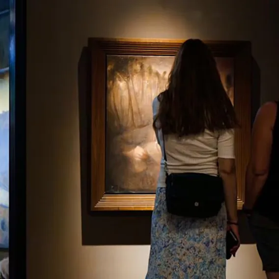To personer ser på kunst i et dempet galleri, og setter pris på maleriene som vises.