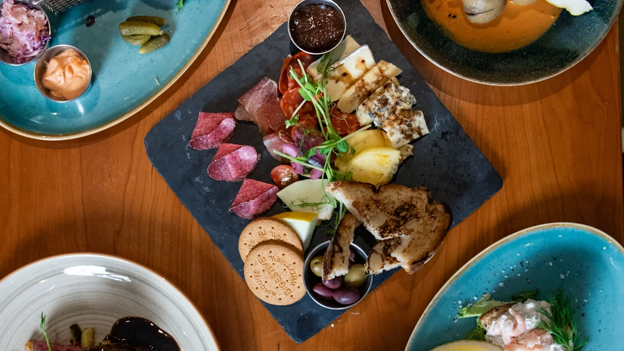 Et lækkert udvalg af forskellige retter, herunder en burger, skaldyr og et charcuteribræt, serveret på Clarion Hotel Örebro.