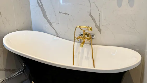 Ylellinen mustavalkoinen tassuamme kultaisilla hanoilla Junior Sviitissä Comfort Hotel Linköping Cityssä.