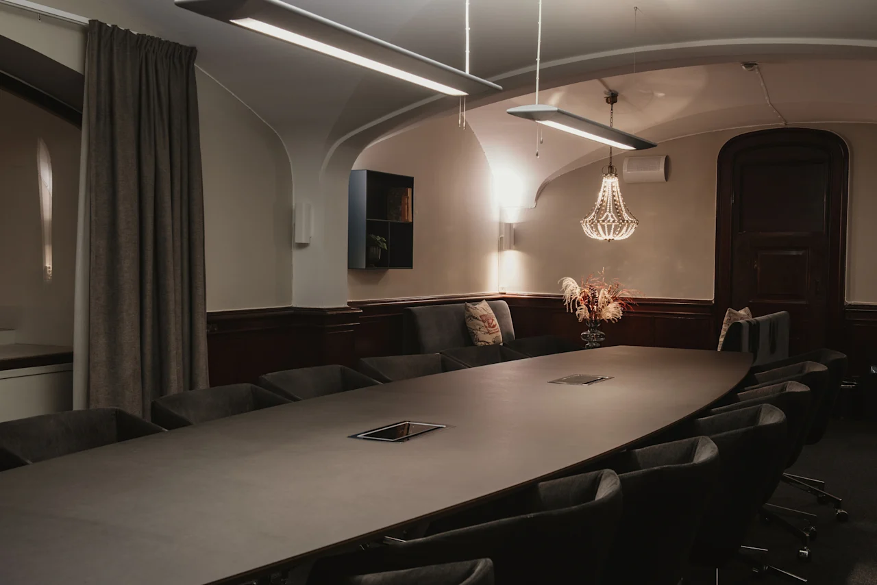 Ett sofistikerat konferensrum på Home Hotel Grand, Helsingborg, med ett långt bord, bekväma sittplatser och elegant belysning, redo för produktiva diskussioner.