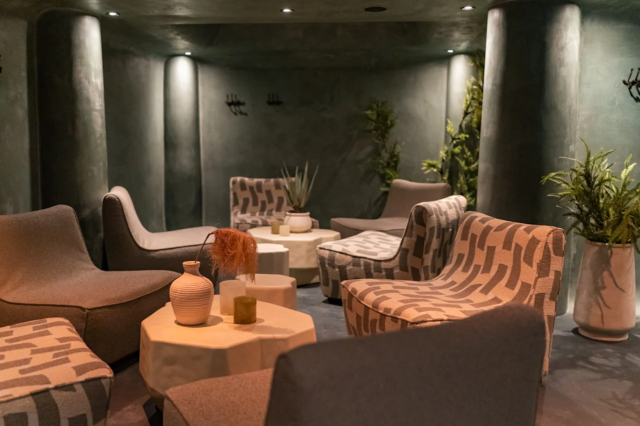 Hämärästi valaistu, kutsuva oleskelutila mukavilla istuimilla, pienillä pöydillä ja ruukkukasveilla, luoden rentouttavan tunnelman.