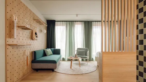 A stylish and modern room at Hobo Oslo with a checkered floor, a wooden pegboard wall, a sofa, and a cozy seating area.