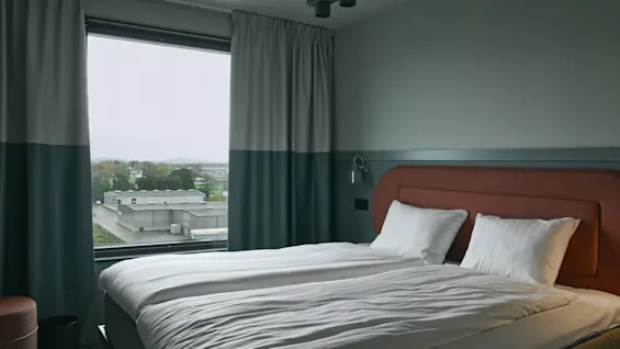 Ett bekvämt hotellrum på Stopover Hotel Falkenberg med två enkelsängar och fönsterutsikt över det omgivande landskapet.